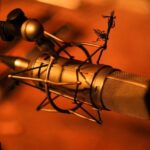 A microphone on a stand in an orange color fazed out background. - (ABCON PR)