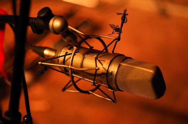 A microphone on a stand in an orange color fazed out background. - (ABCON PR)