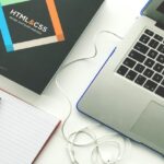 An HTML and CSS textbook with a silver and black laptop to the right. - (ABCON-PR)